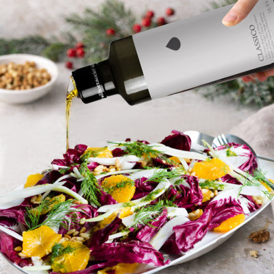 Pouring Italian extra virgin olive oil on winter gourmet salad with radicchio, fennel, and orange