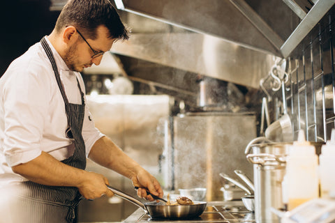 Man chef frying meat pan fire