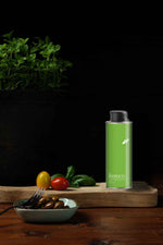 Nostrale Gourmet basil-infused olive oil on cutting board with fresh basil, tomatoes, and olives